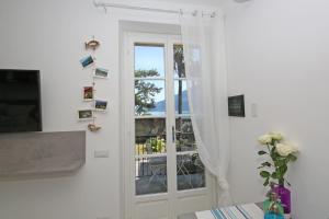 Habitación blanca con ventana y jarrón con flores en Apartment A lago, private beach and parking, en Oliveto Lario