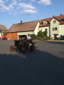 un hombre conduciendo un viejo tractor por una calle en Hanslbauernhof en Moosbach