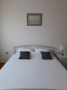 a white bed with black and white pillows on it at Apartman Dunja NS 2 in Novi Sad