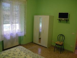 een groene kamer met een televisie, een stoel en een raam bij Home89 in Lucca