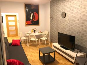 sala de estar con TV y mesa con sillas en Rent0nline Hoża Apartment Center Metro, en Varsovia