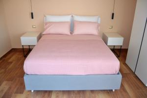 een bed met roze lakens en twee nachtkastjes bij Puteoli house in Pozzuoli +43 foto's