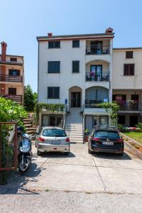 dos autos estacionados en un estacionamiento frente a un edificio en Rooms and Apartments Mofardin, en Rovinj