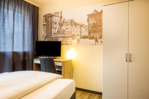 Schlafzimmer mit einem Bett und einem Schreibtisch mit einem TV in der Unterkunft Schroeders City-Style-Hotel in Trier