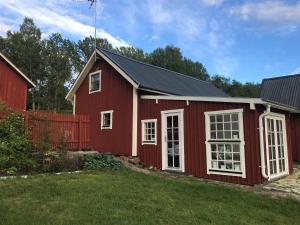 a red barn with white windows and a fence at Sjöbacken Gård in Lerdala