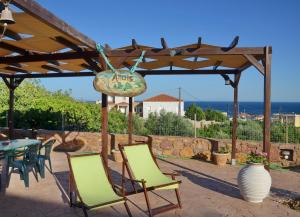 eine Terrasse mit Stühlen, einem Tisch und einem Schild in der Unterkunft Anais Apartments in Chios