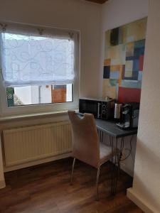 einen Schreibtisch mit Stuhl in einem Zimmer mit Fenster in der Unterkunft Ferienwohnung Steiner in Homburg