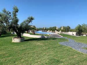 a park with a swimming pool and a tree at Castella Apartments in Vourvourou