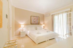 a white bedroom with a white bed and a window at Cape North West in Parga