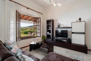 sala de estar con sofá, TV y ventana en Southern Sunny House by An Island Apart, en Calheta