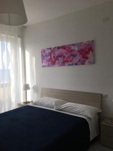 a bedroom with a bed with a painting on the wall at Appartamenti Stella Del Mare in Francavilla al Mare