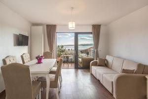 a living room with a table and a couch and a table and chairs at Apartmani Arapovic in Baška Voda