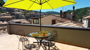 a table and chairs on a balcony with a yellow umbrella at B&B La Soffitta Del Barone in Mormanno