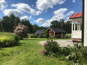 a garden with a red house and a gazebo at Sjöbacken Gård in Lerdala