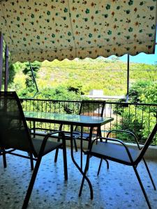 a table and two chairs and an umbrella on a balcony at Neorio Studios in Poros