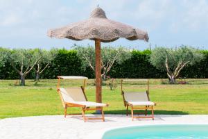 2 sillas bajo una sombrilla junto a una piscina en Casale la Rovere, en Montalto di Castro