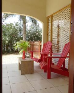 two red chairs and a table on a porch at Yellow Palms in Kralendijk