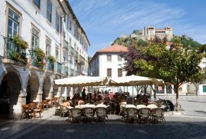 a group of people sitting at tables with umbrellas on a street at Lagar do Sapateiro in Fontes