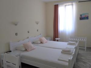 biała sypialnia z 2 łóżkami i oknem w obiekcie Syrianos Hotel w mieście Naksos