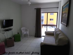 a living room with a couch and a tv and a window at Flat Jardim de Alah in Salvador