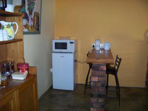a kitchen with a small table and a microwave on top of a refrigerator at Lemontree Cottage in Heidelberg