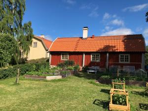 a red house with an orange roof in the yard at Old Wing in Enköping