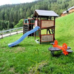 a playground in a field with a slide and scissors at Virtus Et Otium - Feldererhof in Vipiteno