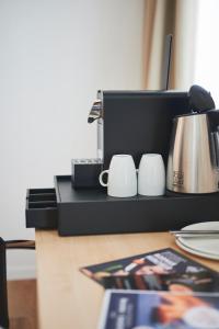 a counter with a coffee pot and cups on it at Hotel Artist in Biel