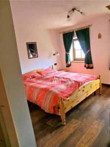 a bedroom with a bed with a red comforter and a window at Virtus Et Otium - Feldererhof in Vipiteno
