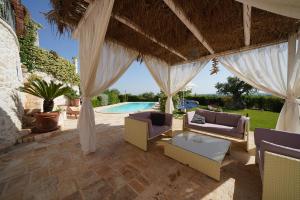 an outdoor patio with a pavilion with chairs and a pool at Villa Belvedere in Ostuni