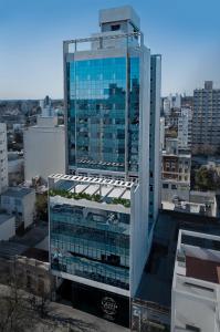 a tall glass building with plants on the roof at Hotel Land Plaza La Plata in La Plata