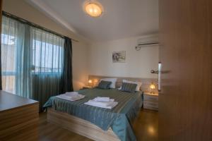 a bedroom with a bed and a large window at Семеен хотел Бриз in Sozopol