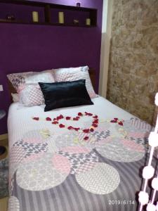ein Bett mit roten Blumen darauf in der Unterkunft Loft "Elegante" Lila in Ubrique