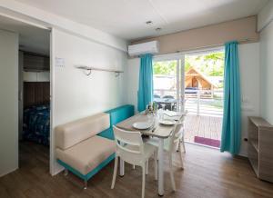 jadalnia ze stołem i krzesłami oraz sypialnia w obiekcie Camping Rose w mieście Dormelletto