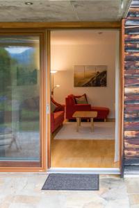 sala de estar con puertas correderas de cristal y sofá rojo en Gartenlodge Auszeit en Nötsch