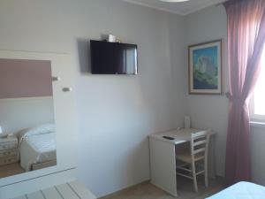 - une chambre avec un lit, un bureau et une télévision dans l'établissement La Radice, à Paganica