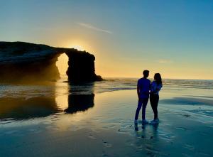 a man and woman standing on the beach at sunset at Os Tres Teixos in San Acisclo