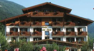 a large building with balconies and plants on it at Hotel des Alpes in Molveno