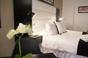 ein Hotelzimmer mit einem Bett und einem Schreibtisch mit einem Telefon in der Unterkunft Pocitos Plaza Hotel in Montevideo