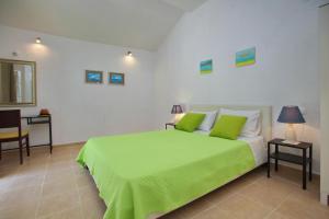 a bedroom with a green bed and a table at Liogerma Cottage in Panormos Skopelos