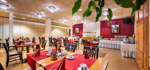 a restaurant with red tables and chairs and a buffet at Schroeders Stadtwaldhotel in Trier