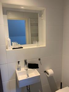 a white bathroom with a sink and a mirror at Koningshof in Alkmaar