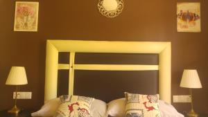 uma cama com uma cabeceira preta e amarela com duas lâmpadas em Hospederia V Centenario em Estepona