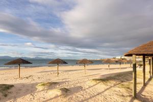 a group of straw umbrellas on a beach at SantoSea in Mossel Bay