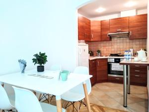 a kitchen with a white table and white chairs at Chill & Explore by Cooee Apartments in Warsaw