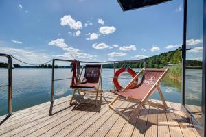 two chairs sitting on a dock next to the water at Apartament Na Wodzie in Ruciane-Nida
