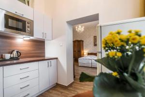 een keuken met witte kasten en een vaas met gele bloemen bij RETRO Apartments Bosak in Prešov