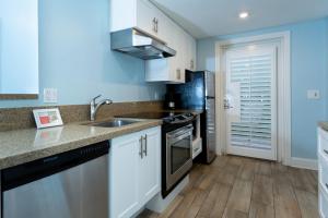 eine Küche mit weißen Schränken, einer Spüle und einem Kühlschrank in der Unterkunft Crane's Beach House Boutique Hotel & Luxury Villas in Delray Beach