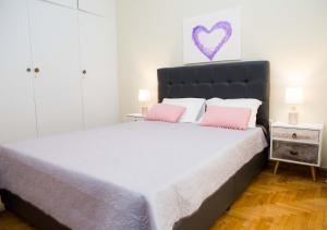 a bedroom with a large bed with two pink pillows at Acropolis,Historic center Apartment-update in Athens
