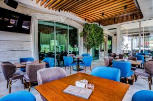 a restaurant with wooden tables and blue chairs at Hotel Odissey Jaz in Budva